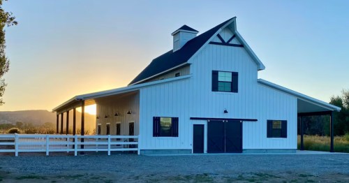 The sun slowly rises behind a white barn Airbnb in Rigby, Idaho.