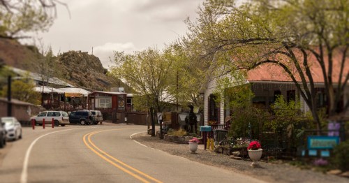 Curving main street in Madrid, New Mexico, lined with historic shops and art galleries beneath desert hills.