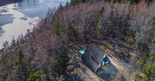 Oceanfront A-frame on Little Kennebec Bay, with a hot tub visible next to the cabin in the trees.