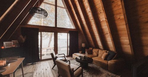 The interior living room of an A-frame cabin with large windows.