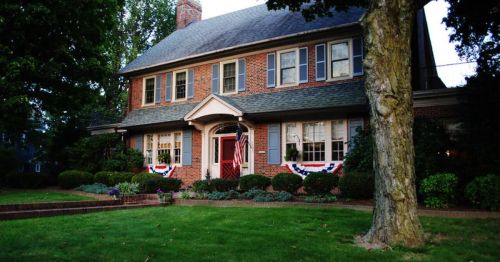 A red brick house with American flags draped on the windows.