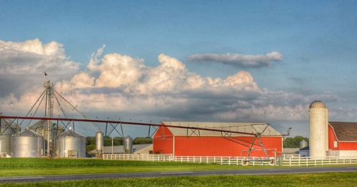 A red barn and farm equipment in a field.