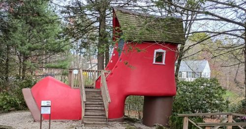 A sculpture of a giant red shoe that is large enough to walk on.