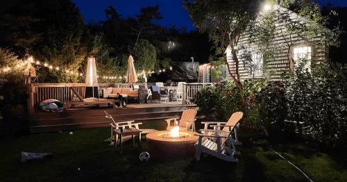 A nighttime view of the deck and fire pit at the Goose Airbnb rental property in Nantucket, Massachusetts.