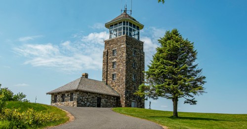 view of the Quabbin Reservoir Observation Tower, a stone tower surrounded by grass under a blue sky in ware, massachusetts