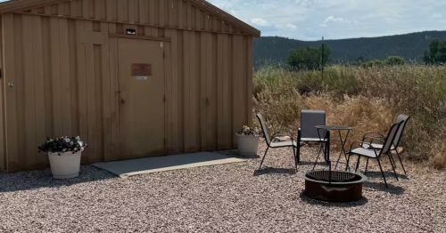 The exterior of a barracks turned short-term rental with an outdoor fire pit and chairs.