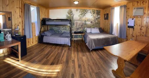The interior of a one-bedroom cabin with a full-size bed, bunk beds, and a table.