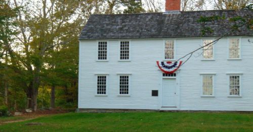 The exterior of a white building with an American flag draped on it.