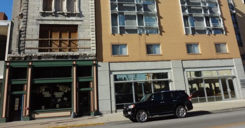View of a downtown area with a black car in front of the storefronts.