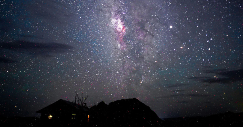 Brilliant star-filled night sky over a Texas cabin in the desert.