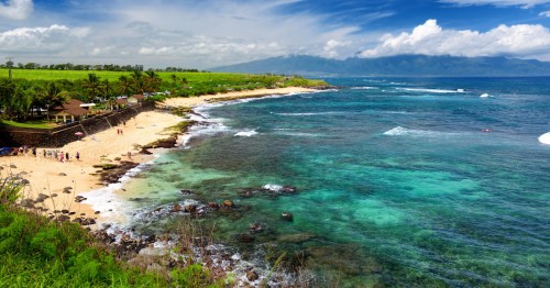 Turquoise water crashes onto a beautiful beach on a sunny Hawaiian day.
