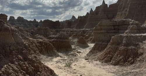 As always in Badlands National Park, it’s best to avoid hiking in the heat of the day. An early morning hike or toward sunset is your sweet spot. While the Door Trail is a short-and-sweet in-and-out trek, you’re still going to cover some rough terrain. The trail begins on a boardwalk, but you’ll quickly head down a set of stairs to a primitive trail. Here, you’ll need to follow the trail that is marked with yellow posts. Be sure to stay on the marked trail. This is both for the protection of the landscape and for your benefit. It's not uncommon to find prairie rattlesnakes scurrying across the trail. While it's only a 32-foot elevation gain, you’re going to want a good pair of shoes to tackle the terrain. When on the boardwalk portion of the trail, you’ll be treated to rock formations rising seemingly out of nowhere from the Midwest prairie. Once you get off the boardwalk, you’ll get up close and personal with the rock formations and be treated to panoramic views of the canyon below.