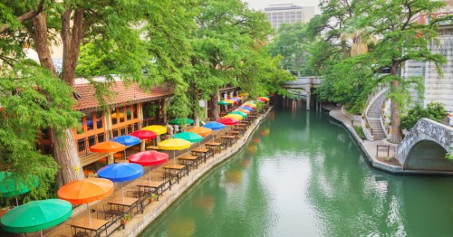 Colorful umbrellas and lush greenery line the San Antonio River Walk in Texas.