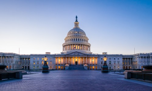 United States Capitol Building in Washington, D.C., at sunset, with a glowing sky and the reflecting pool in the foreground.