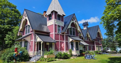 Exterior of red Victorian home that now functions as Salted Butter Cafe, surrounded by green grass under a blue sky.