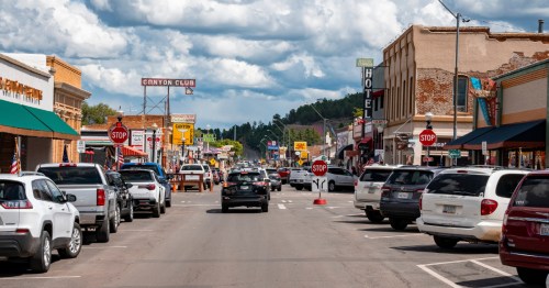 Busy downtown Williams, Arizona, filled with travelers exploring Route 66 shops, vintage signage, and the Canyon Club under a cloudy afternoon sky.