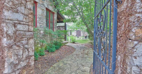 Inviting garden gate entrance framed by ivy-covered stone walls at a serene Texas winery Airbnb courtyard.