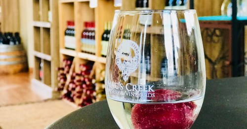 A glass of white wine with fruit in the lobby of a winery.