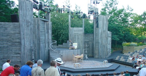 A tall, wooden stage surrounded by green woods and an audience at American Players Theatre