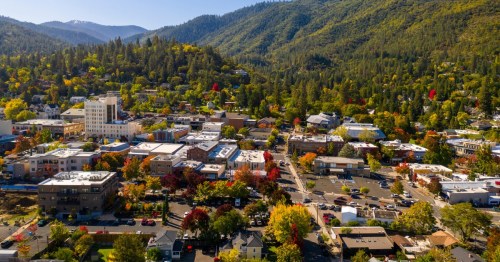 A mountain town is in the grasp of fall with changing colors among the green hills.