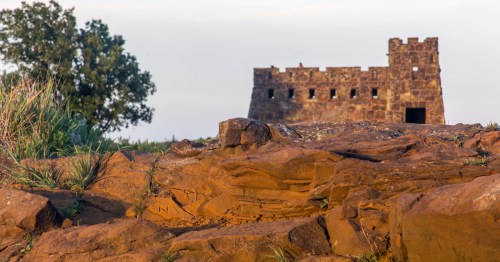 Reddish brown dirt on a hill leading up to the sandstone castle known as Coronado Heights