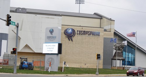 An ivory brick building with a blue and black sign that says Cosmophere