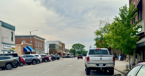 A row of cars along the road along rows of stores in downtown Spring Green