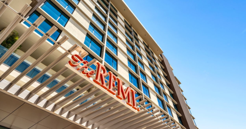 a shot of the remi hotel's red sign taken from below with a blue sky above