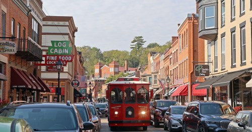 Red trolley on a main street line with brick buildings.