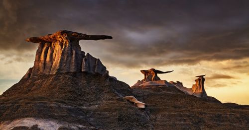 Hoodoo rock formations at Bisti/De-Na-Zin Wilderness in NM, under a dark, gloomy sky.