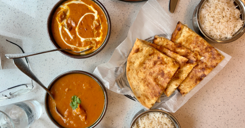 view of two bowls of curry, a plate of naan, and two bowls of rice at keshar, an indian restaurant on cape cod