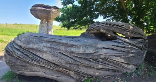 one large rock formation sits in the foreground while a rock formation shaped like a mushroom at mushroom rock state park in Kansas