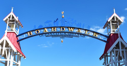 the welcome sign for the ocean city boardwalk in maryland against a blue sky