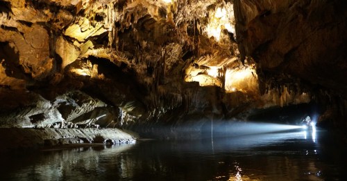 a boat light illuminates the interior of penn's cave along an undergroud river