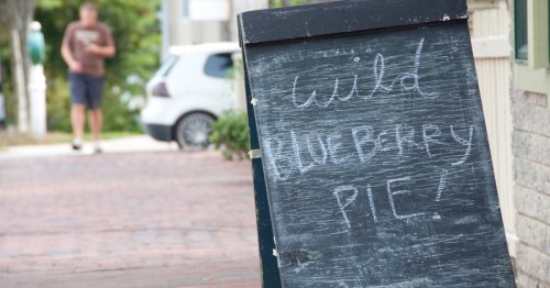 A runner runs near a chalkboard sign that says "wild blueberry pie."