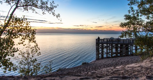 An orange and blue sunset over the blue water of Lake Michigan along the Sleeping Bear Dunes