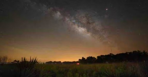 Milk way in clear sky with orange glow above ranch Airbnb in Florida