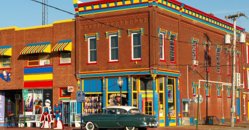 A red brick building decorated with red, yellow and blue painted features and Superman memorabilia out in front and in the windows.