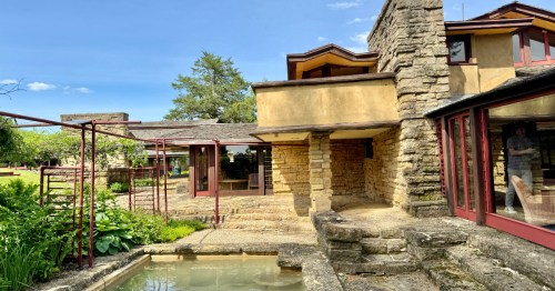 A close up of the ivory stone exterior of Taliesin with a small pool in the foreground.