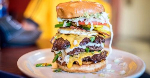 Massive double-patty burger with cheese, jalapeños, and a fried egg stacked on a bun. 
