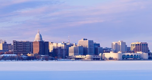 Winter panorama of Madison, Wisconsin, with a snow covered lake in the foreground and dowtown with the capitol building in the background.