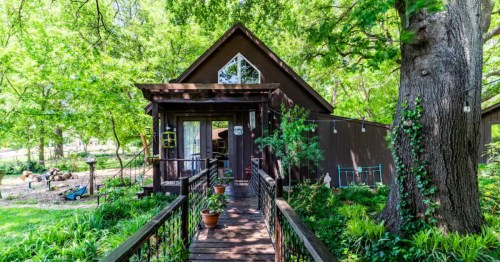 exterior of a treehouse-like csbin with a long walkway leading to the front door in oklahoma on a sunny summer day