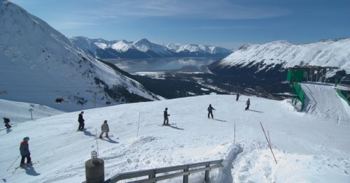 Alyeska Resort skiers enjoying the slopes with mountain and lake views in Girdwood, Alaska.