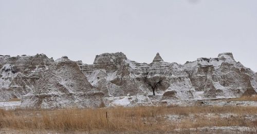 Large rock formations rising from a prairie with a snow dusting on them.