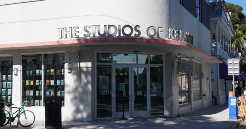 Exterior of The Studios of Key West, a white building with a groundstore bookshop with books displayed in the windows