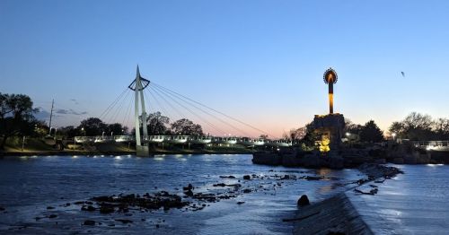A river with a bridge and a statue in the background.