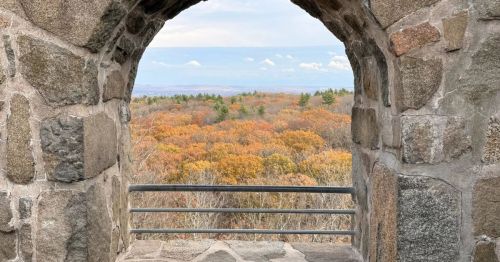 A window in a stone castlye overlooking a colorful fall forest.