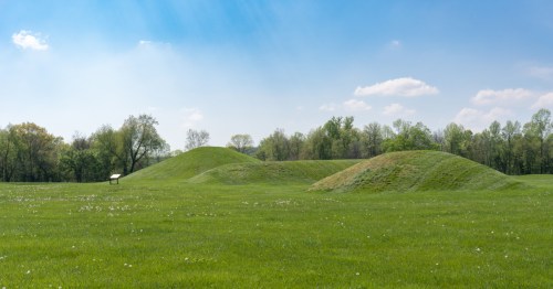 Earthen mounds of grass lie under a blue sky
