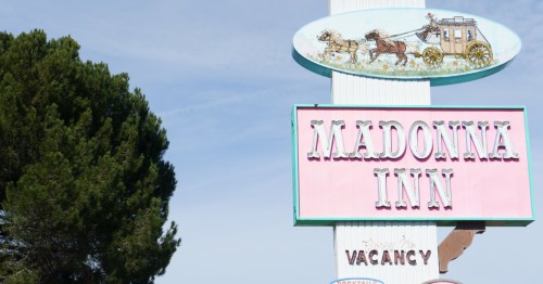 Looking up at the Madonna Inn sign on a clear, blue-sky day.
