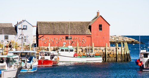 Boats sit in front of the red Motif #1 fishing shack in Rockport, Massachusetts.
